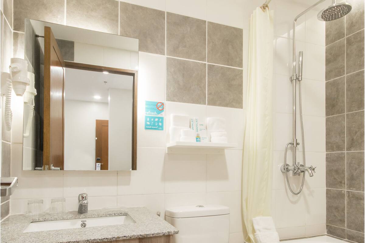 A bathroom with a sink, mirror, toilet, shower, and towel rack.
