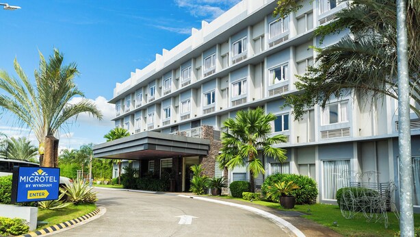 Un hotel de varios pisos con fachada plana, entrada cubierta y un cartel que indica que es un Microtel by Wyndham.
