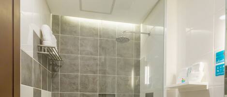 Un baño moderno con ducha envuelta en vidrio, inodoro y tocador con encimera de granito.