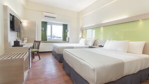 Habitación de hotel con dos camas, un escritorio con silla, televisor montado en la pared y ventana con cortinas.