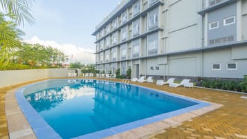 Una piscina al aire libre, sombrillas, sillones reclinables de piscina