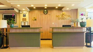 Una mesa de recepción con un reloj, una placa y un letrero que dice 'MICROTEL BY WYNDHAM'.