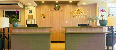 Una mesa de recepción con un reloj, una placa y un letrero que dice 'MICROTEL BY WYNDHAM'.