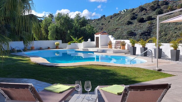 A swimming pool with a white building in the background, surrounded by greenery and hills. - 🦎Charming gem with pool in the mountains. Located 20min sw. from Las Palmas 🦎 (santa brigida)