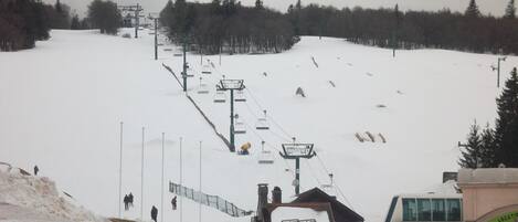 A ski lift, a building, and a snow-covered slope.