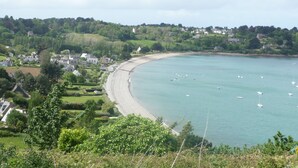 Une ville côtière avec une plage de sable, des bateaux sur l’eau et des maisons le long de la côte.