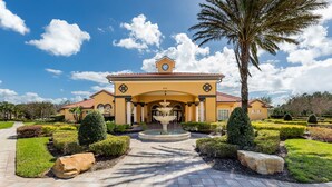 A large, yellow building with a fountain in the center, surrounded by well-manicured gardens and palm trees.