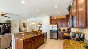 A spacious kitchen with granite countertops, stainless steel appliances, and wooden cabinets.