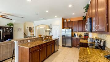 A spacious kitchen with granite countertops, stainless steel appliances, and wooden cabinets.