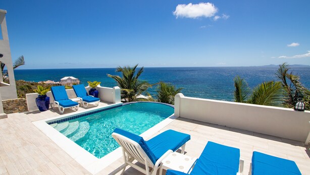 Zona piscina con lettini prendisole e vista sull'oceano.