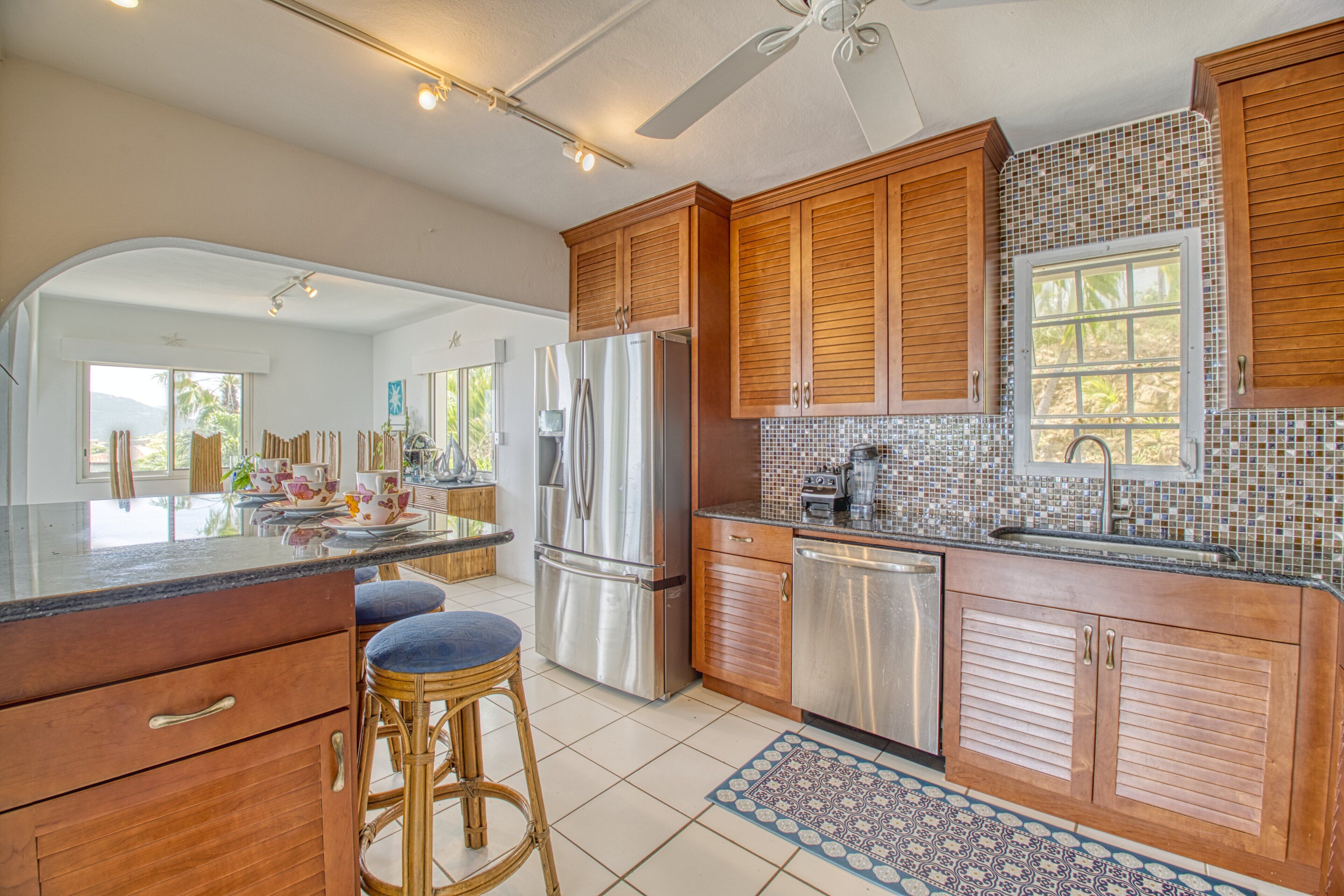 A modern kitchen with wooden cabinets, stainless steel appliances, and a large island with stools.
