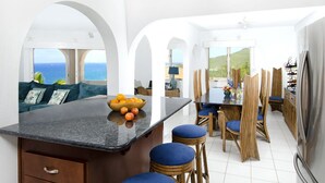 Una cucina moderna con un'isola centrale, un'area pranzo con sedie di legno e vista sul mare.