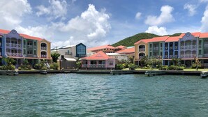 A waterfront hotel with colorful buildings, a dock, and a mountain in the background.