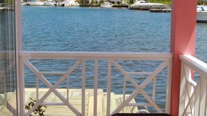 A balcony with a view of the water, a chair, and a railing.