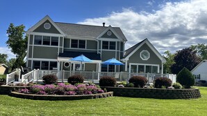 A two-story house with a porch, a small deck, and a stone retaining wall with flowers. - Powers Lake spacious retreat (Powers Lake)