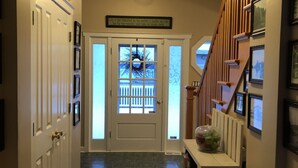 A hallway with a patterned rug, a wooden bench with a vase, and a staircase with wooden railings. - Powers Lake spacious retreat (Powers Lake)