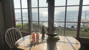 A round table with two bottles and two glasses, a teapot, and a tray with utensils. - Snug Harbor Inn - Midship Cottage (Sturgeon Bay)