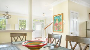 Un coin repas avec une table en bois, des chaises, un bol coloré et un tableau accroché au mur.