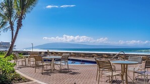 A beachfront patio with lounge chairs and a pool, overlooking the ocean. - Updated OceanFront Whale Watching - Kulakane 211 (Lahaina)