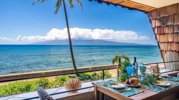 A dining area with a view of the ocean and a mountain in the distance. - Updated OceanFront Whale Watching - Kulakane 211 (Lahaina)