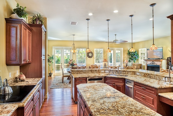 A spacious kitchen with granite countertops, wooden cabinets, and pendant lighting.