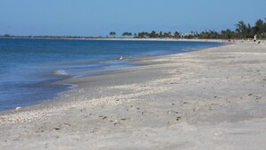 A beach with clear blue water, a sandy shore, and a few people in the distance. -  FREE golfcart and bicycles, Perfect location, 5 star reviews, beautiful home ! (captiva island)