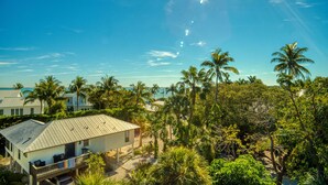 A beachfront property with a house, palm trees, and a clear blue sky. -  FREE golfcart and bicycles, Perfect location, 5 star reviews, beautiful home ! (captiva island)