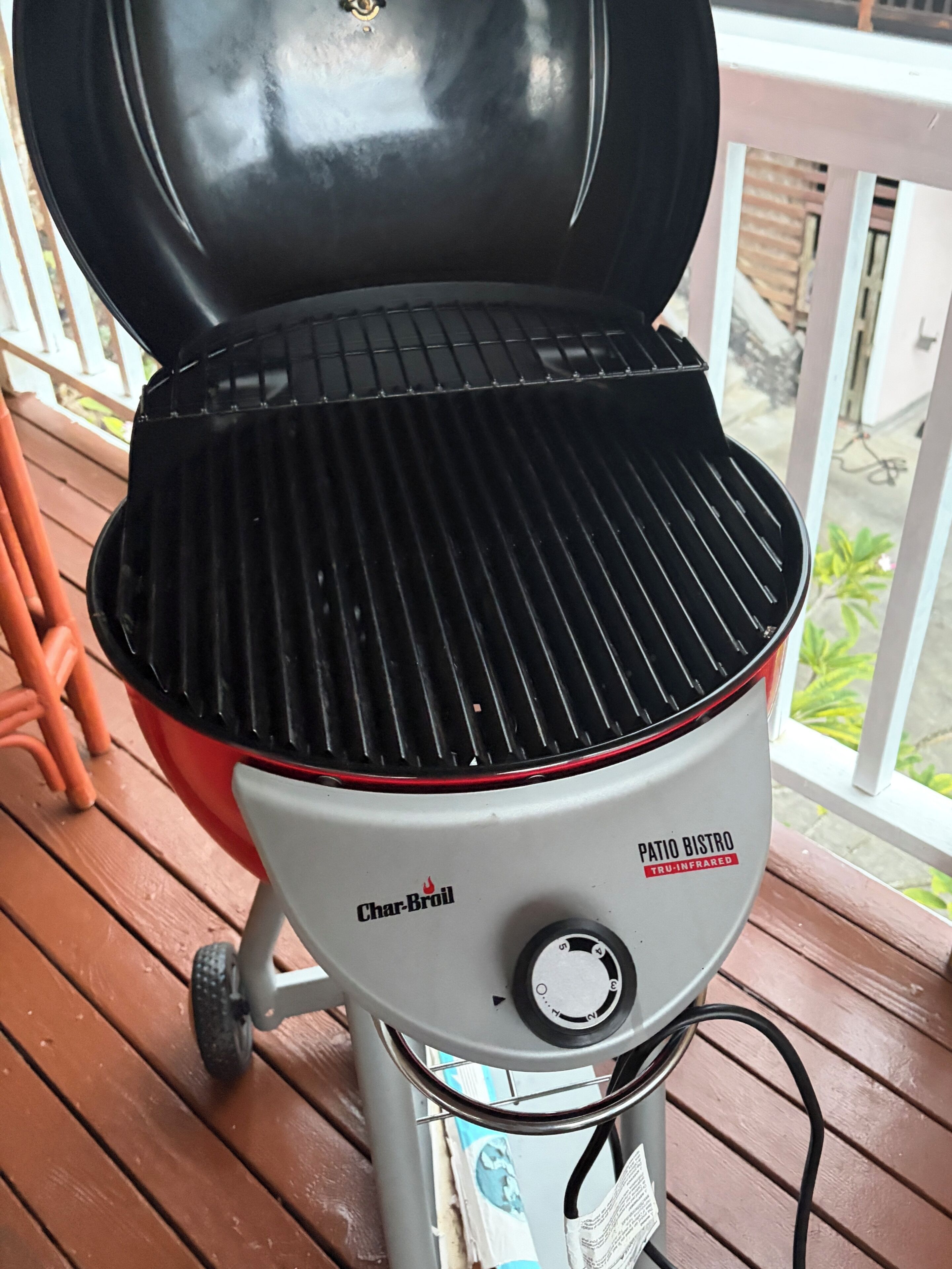 Un barbecue d’extérieur Char-Broil, de type « bistro », doté d’un bouton de réglage, placé sur une terrasse en bois.