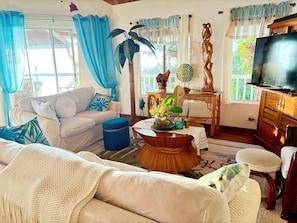 A living room with a sofa, a coffee table, a television, and a window with curtains.