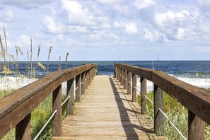 A wooden boardwalk leading to the beach with a clear view of the ocean.