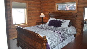 Un dormitorio con paneles de madera, una cama, una mesita de noche, una lámpara y una ventana.