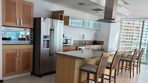 A modern kitchen with a central island, wooden cabinets, stainless steel appliances, and a view of high-rise buildings. - Peninsula Vallarta-Luxurious/Huge Oceanfront Condo w/ Spectacular View (Puerto Vallarta)