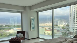 A bedroom with a large bed, a chair, a view of the city, and a ceiling fan. - Peninsula Vallarta-Luxurious/Huge Oceanfront Condo w/ Spectacular View (Puerto Vallarta)