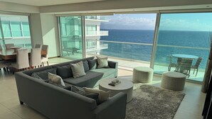 A modern living room with a grey sofa, a coffee table, and a view of the ocean through large windows. - Peninsula Vallarta-Luxurious/Huge Oceanfront Condo w/ Spectacular View (Puerto Vallarta)