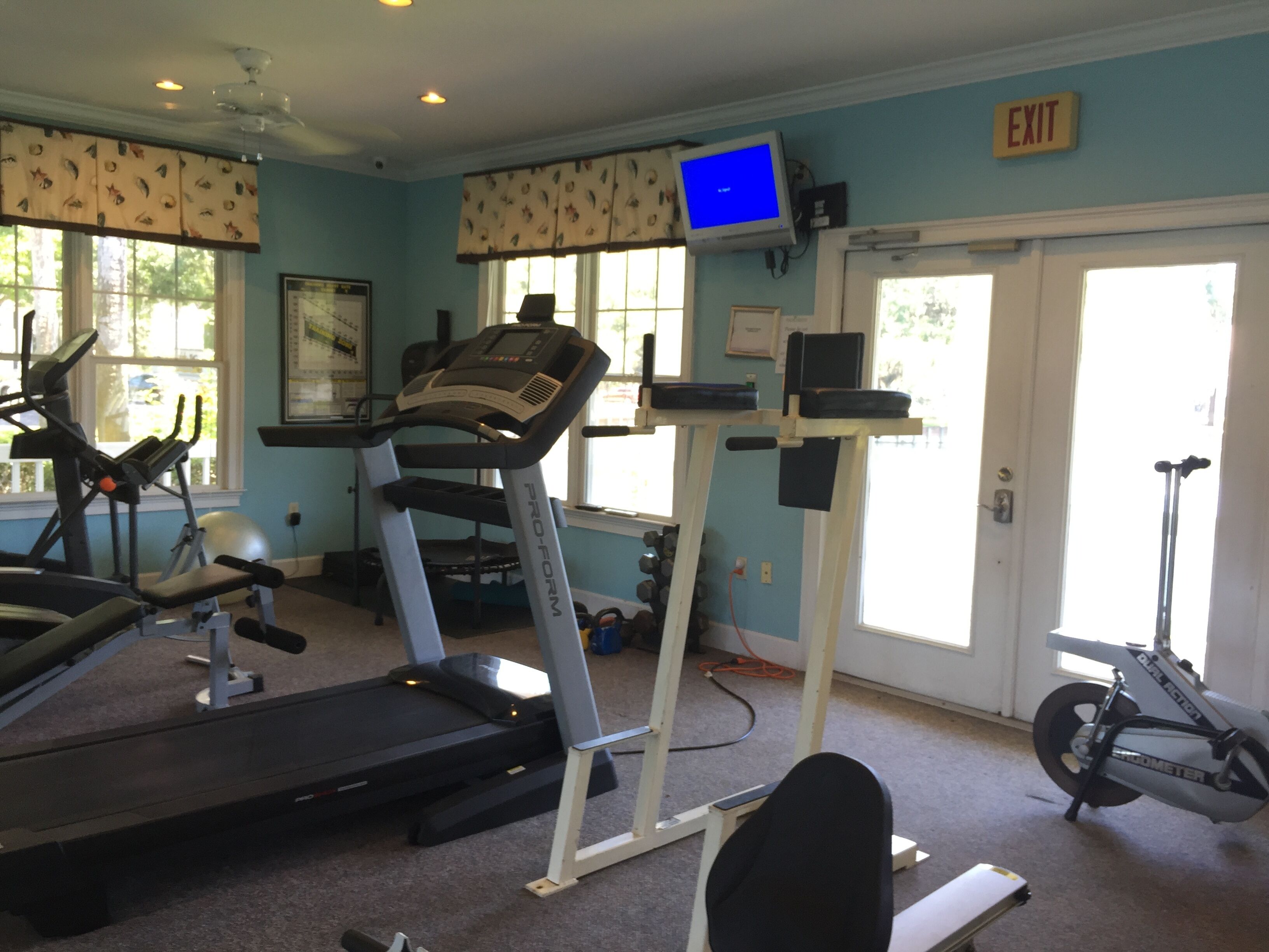 Une salle de sport équipée de tapis de course, de vélos d’appartement et d’autres appareils d’exercice.