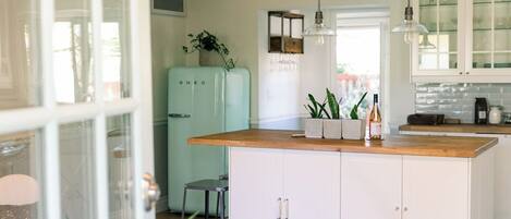 Een moderne keuken met witte kastjes, een lichtblauwe koelkast en een houten aanrecht.