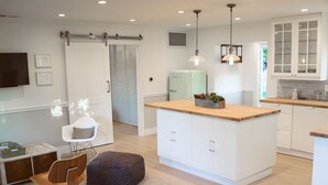 Une cuisine moderne avec des meubles blancs, un îlot central en bois et des luminaires suspendus.