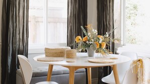Un espace repas moderne avec une table ronde, des chaises blanches et un vase de fleurs.