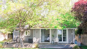 Une maison avec un patio à l’arrière, une piscine et un arbre.