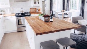 Une cuisine moderne dotée d’un îlot central en bois, d’appareils électroménagers intégrés et d’un coin repas avec une table et des chaises.