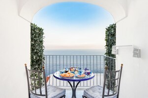 Un balcón con una mesa dispuesta para una comida, con vista al mar.