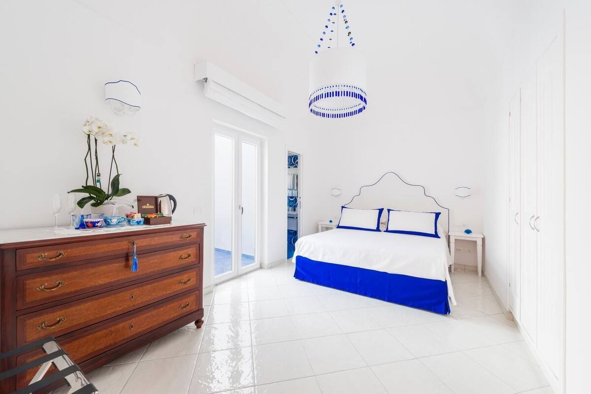 A bedroom with a bed, dresser, and a potted plant.