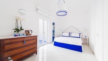 A bedroom with a bed, dresser, and a potted plant.