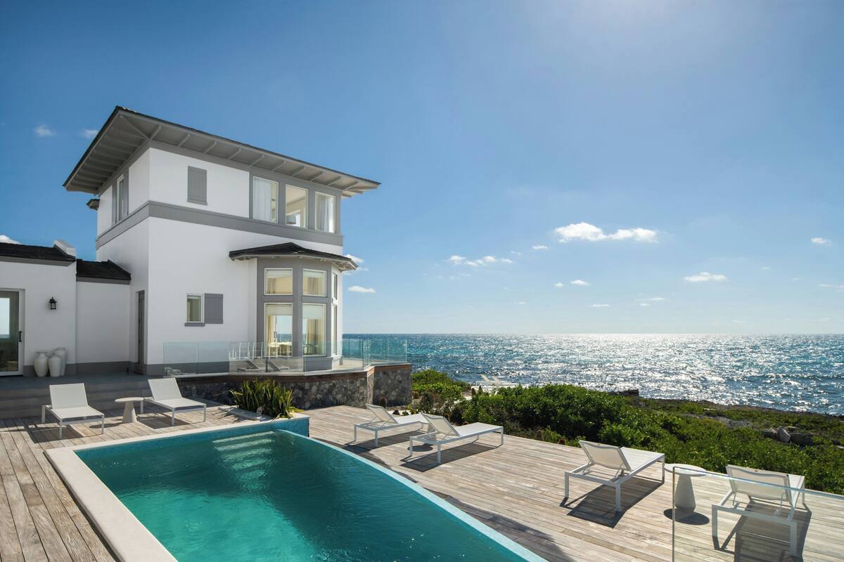 A modern two-story house with a pool and ocean view.