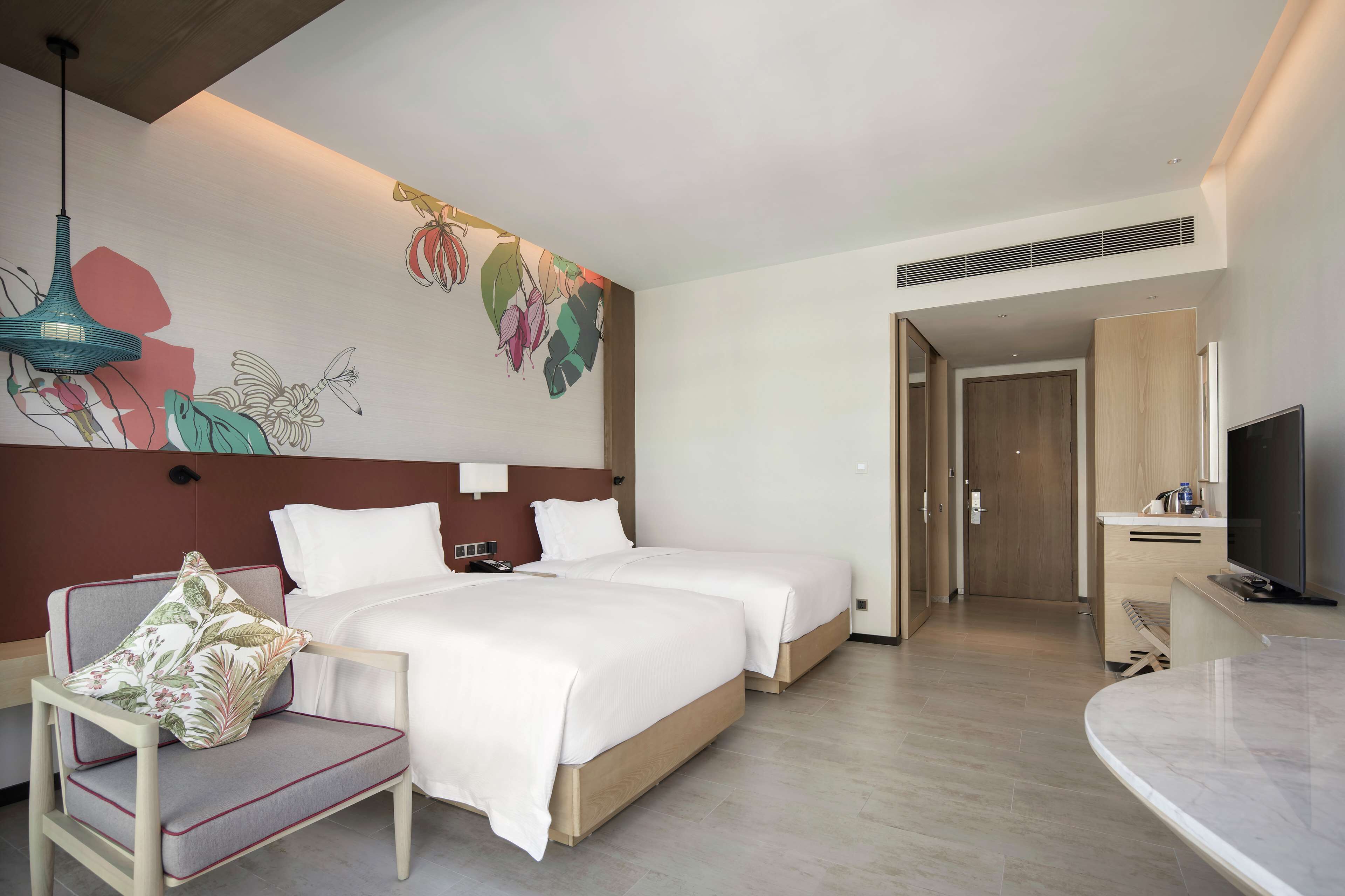 Une chambre d’hôtel avec deux lits, une télévision, un bureau et une chaise.