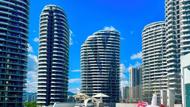 A swimming pool with a view of high-rise buildings and a unicorn float. - Hilton Garden Inn Sanya (Sanya)
