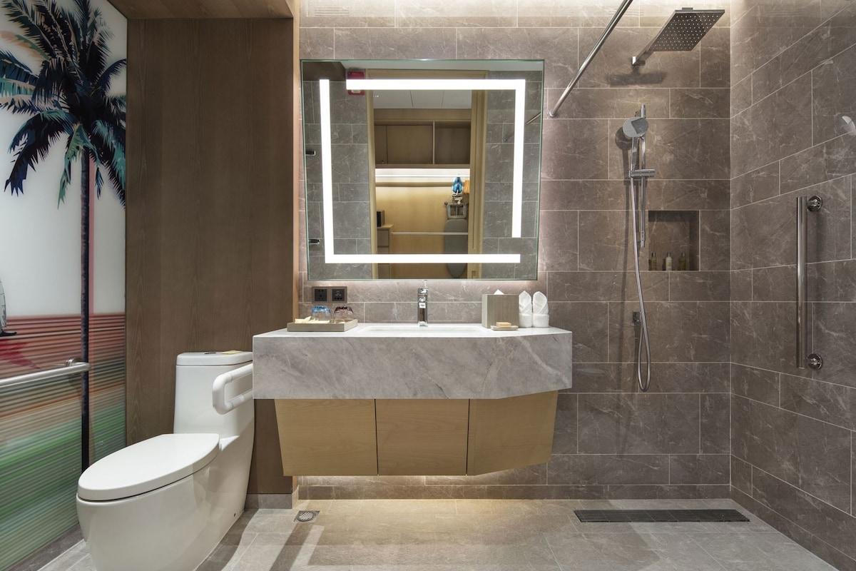 A modern bathroom with a marble sink, a glass shower enclosure, and a toilet.
