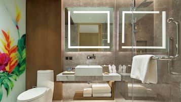 A modern bathroom with a glass-enclosed shower, a large mirror, a white sink, and a toilet.