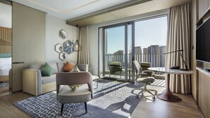 A modern hotel room with a large balcony, a sofa, a chair, a desk, and a TV. - Hilton Garden Inn Sanya (Sanya)