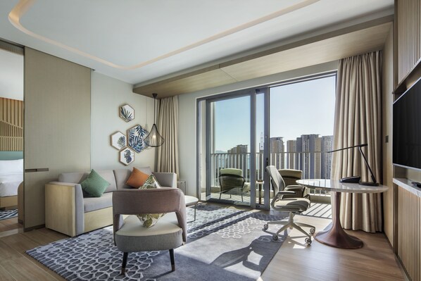 A modern hotel room with a large balcony, a sofa, a chair, a desk, and a TV. - Hilton Garden Inn Sanya (Sanya)